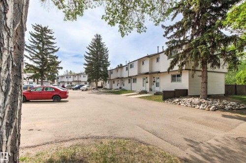 Townhome row featuring white siding exteriors, individual front entrances, and mature evergreen landscaping - 707 Clareview Road, Edmonton, AB - Outdoor