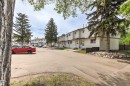 Townhome row featuring white siding exteriors, individual front entrances, and mature evergreen landscaping - 707 Clareview Road, Edmonton, AB  - Outdoor 