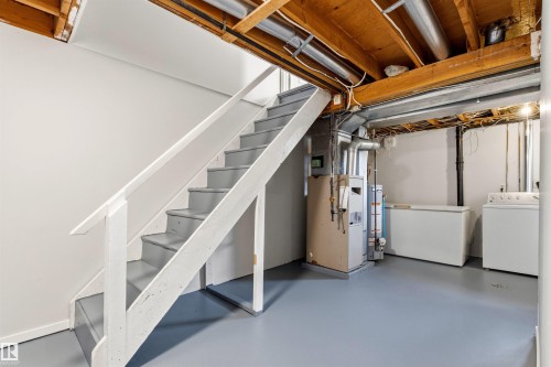 Basement area featuring a painted wooden staircase with handrail, exposed wood ceiling joists, and a light gray finished floor - 707 Clareview Road, Edmonton, AB - Indoor Photo Showing Laundry Room