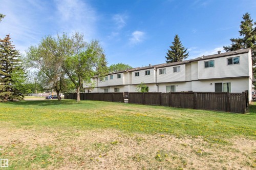 Rear exterior of a multi-unit property featuring white siding and dark brown fencing - 707 Clareview Road, Edmonton, AB - Outdoor