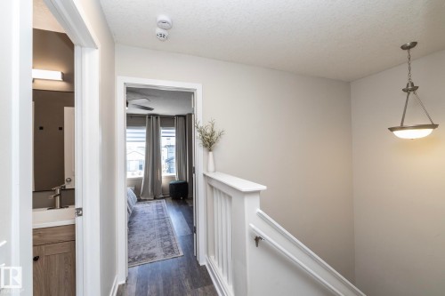 Well-lit hallway featuring wood-finish flooring, white trim, and a ceiling-mounted pendant light fixture - 4204 161 Avenue, Edmonton, AB - Indoor Photo Showing Other Room