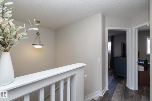 Stairwell featuring white railing, textured ceilings, and a pendant light fixture - 4204 161 Avenue, Edmonton, AB - Indoor Photo Showing Other Room