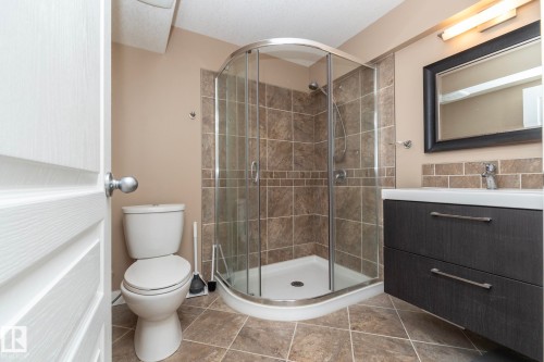 Bathroom featuring a corner glass-enclosed shower, a modern floating vanity with integrated sink, and square floor tiles - 4204 161 Avenue, Edmonton, AB - Indoor Photo Showing Bathroom