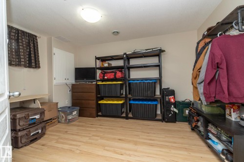 Versatile room featuring wood-finish flooring, neutral wall tones, and a window with patterned curtains - 4204 161 Avenue, Edmonton, AB - Indoor