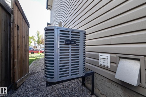 Ameristar air conditioning unit on a metal stand, set against beige horizontal siding - 4204 161 Avenue, Edmonton, AB - Outdoor