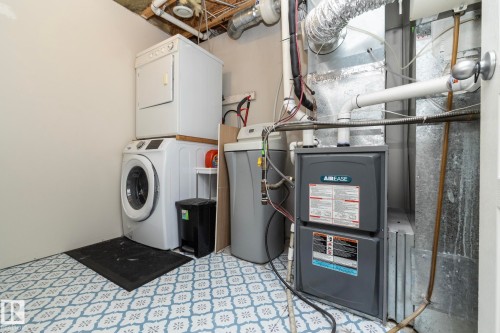 Dedicated utility space featuring patterned floor tile, a stacked washer and dryer, and a water softener system - 4204 161 Avenue, Edmonton, AB - Indoor Photo Showing Laundry Room