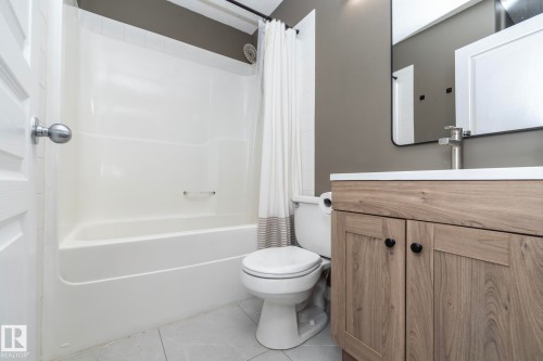 Bathroom featuring a white shower-over-tub combination, a toilet, and a wood-finish vanity with a white countertop and rectangular sink - 4204 161 Avenue, Edmonton, AB - Indoor Photo Showing Bathroom