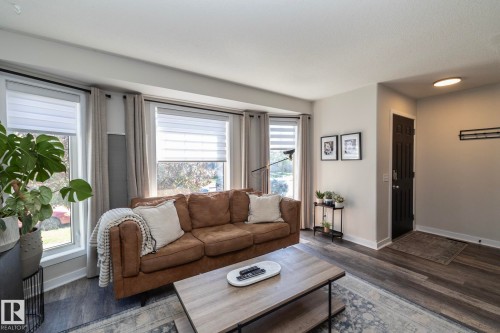 Living area featuring wood-finish flooring, a three-window bay, and a dark paneled entry door - 4204 161 Avenue, Edmonton, AB - Indoor Photo Showing Living Room