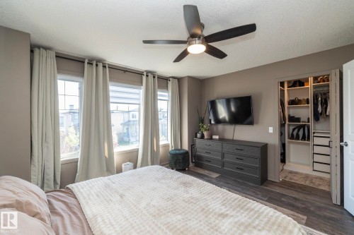 Spacious room featuring wood-finish flooring, a contemporary ceiling fan with integrated lighting, and three large windows - 4204 161 Avenue, Edmonton, AB - Indoor Photo Showing Bedroom