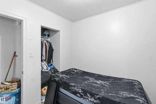 White walls featuring a built-in closet with hanging rod and shelving - 16 Michigan Street, Devon, AB - Indoor Photo Showing Bedroom