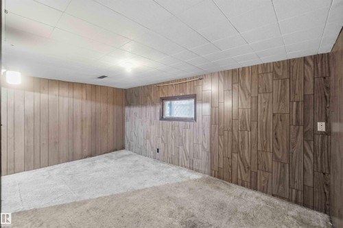 Carpeted room featuring wood-finish paneling and a drop ceiling - 16 Michigan Street, Devon, AB - Indoor