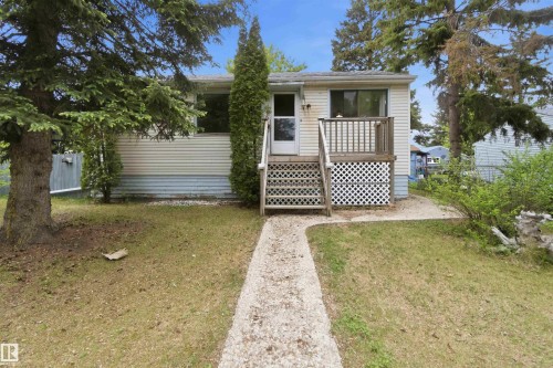 Single-story residence featuring light-colored horizontal siding and a front porch with white lattice detailing - 16 Michigan Street, Devon, AB - Outdoor With Deck Patio Veranda