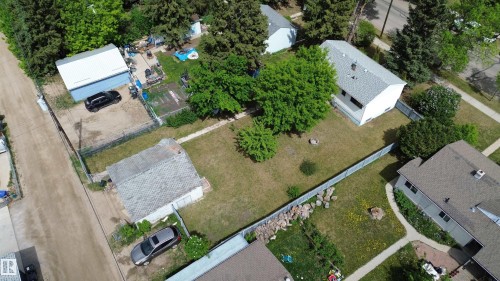 Expansive property featuring a white single-story residence with a gray shingle roof, a detached garage with a light blue exterior, and a secondary outbuilding - 16 Michigan Street, Devon, AB - Outdoor With View
