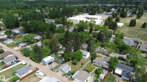 Aerial view showcasing a residential area with mature trees and a distant mountainous backdrop - 16 Michigan Street, Devon, AB - Outdoor With View