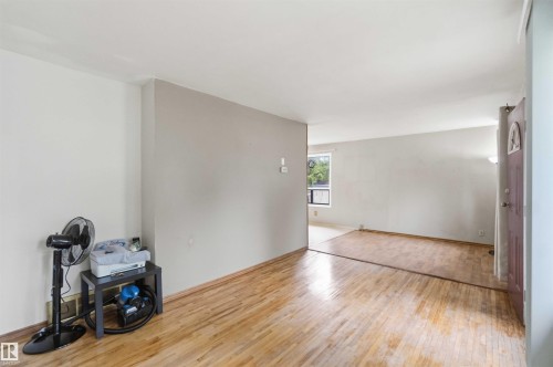 Bright interior space featuring wood-finish flooring, light-toned wall paint, and a window providing natural illumination - 16 Michigan Street, Devon, AB - Indoor Photo Showing Other Room