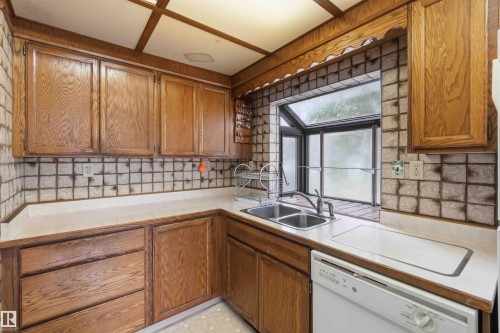 Kitchen featuring wood cabinetry, a double basin stainless steel sink, a tiled backsplash, laminate countertops, and a garden window - 16 Michigan Street, Devon, AB - Indoor Photo Showing Kitchen With Double Sink
