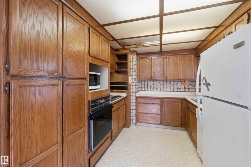 Kitchen featuring extensive wood cabinetry, white laminate countertops, and patterned vinyl flooring - 16 Michigan Street, Devon, AB - Indoor Photo Showing Kitchen
