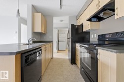Kitchen featuring light wood-finish cabinetry, black appliances, a double basin stainless steel sink, and a dishwasher - 