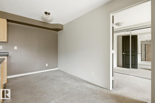 Carpeted room with light grey walls and a contrasting accent wall - 312 13908 136 Street Nw, Edmonton, AB - Indoor