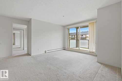 Spacious room featuring light-toned carpeting and neutral wall paint - 312 13908 136 Street Nw, Edmonton, AB - Indoor Photo Showing Other Room