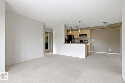 Open-concept living area featuring light-toned carpeting and neutral wall finishes - 312 13908 136 Street Nw, Edmonton, AB - Indoor Photo Showing Kitchen