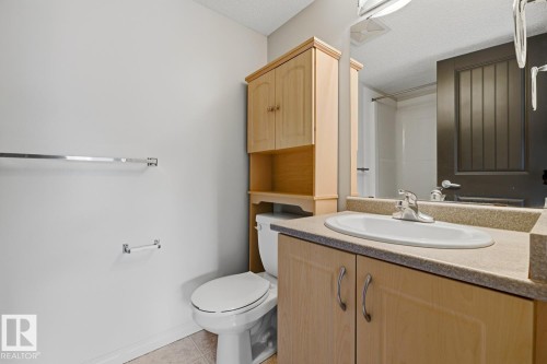 Bathroom vanity with an integrated sink, laminate countertop, and wood-finish cabinetry - 312 13908 136 Street Nw, Edmonton, AB - Indoor Photo Showing Bathroom