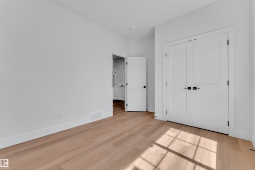 Light wood-finish flooring complements crisp white walls and trim - 6092 179 Ave Nw, Edmonton, AB - Indoor Photo Showing Other Room
