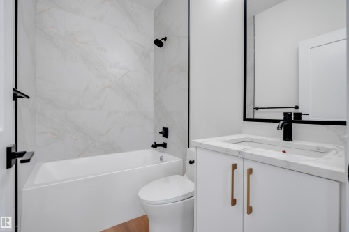 Bathroom featuring a white vanity with gold-tone hardware, a rectangular undermount sink, and a countertop with natural stone-look veining - 6092 179 Ave Nw, Edmonton, AB - Indoor Photo Showing Bathroom