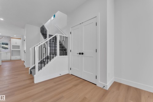 Entry foyer featuring wood-finish flooring and a staircase with black metal balusters and white risers - 6092 179 Ave Nw, Edmonton, AB - Indoor Photo Showing Other Room
