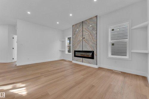 Modern electric fireplace with a large-format stone-look surround - 6092 179 Ave Nw, Edmonton, AB - Indoor With Fireplace