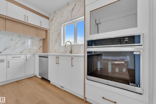 Modern kitchen featuring white cabinetry, light wood-finish accents, and gold-toned hardware - 6092 179 Ave Nw, Edmonton, AB - Indoor Photo Showing Kitchen