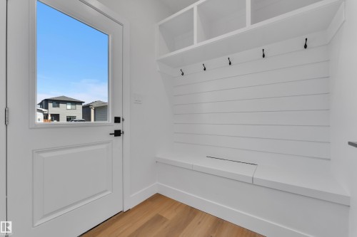 Entryway featuring wood-finish flooring, a white paneled door with a clear glass insert, and matte black hardware - 6092 179 Ave Nw, Edmonton, AB - Indoor Photo Showing Other Room