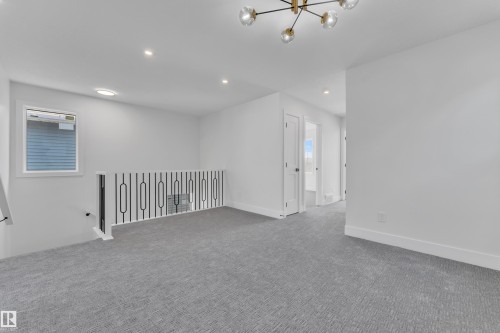 Upper-level landing featuring light gray carpeting, white walls, and a modern black and gold chandelier - 6092 179 Ave Nw, Edmonton, AB - Indoor Photo Showing Other Room