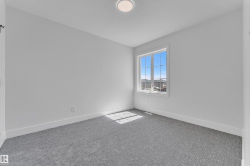 Spacious room featuring light gray walls, a textured gray carpet, and a large window with white trim - 6092 179 Ave Nw, Edmonton, AB - Indoor Photo Showing Other Room