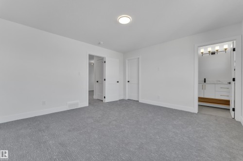Spacious room featuring light grey patterned carpeting, crisp white walls, white baseboards, and a flush-mount ceiling light - 6092 179 Ave Nw, Edmonton, AB - Indoor Photo Showing Other Room