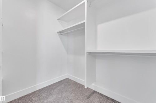 Walk-in closet with white shelving, hanging rods, and grey patterned carpet flooring - 6092 179 Ave Nw, Edmonton, AB - Indoor With Storage