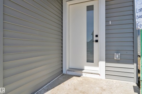 Contemporary entry door with frosted glass panel and matte black hardware, framed by light gray siding - 6092 179 Ave Nw, Edmonton, AB - Outdoor With Exterior