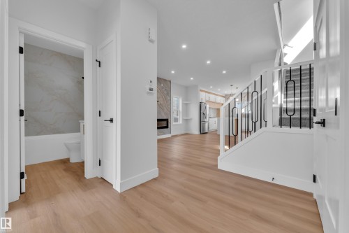 Light wood-finish flooring throughout the main level - 6092 179 Ave Nw, Edmonton, AB - Indoor Photo Showing Other Room