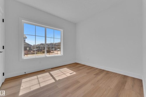Bright interior room with wood-finish flooring and a large multi-pane window - 6092 179 Ave Nw, Edmonton, AB - Indoor Photo Showing Other Room