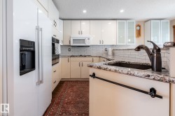 Kitchen featuring a white side-by-side refrigerator, cream-colored cabinetry, light granite countertops, a subway tile backsplash, and recessed lighting - 