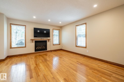 Living area featuring rich wood-finish flooring, an inset fireplace with a wood mantle, and recessed ceiling lighting - 4632 151 Street, Edmonton, AB - Indoor With Fireplace