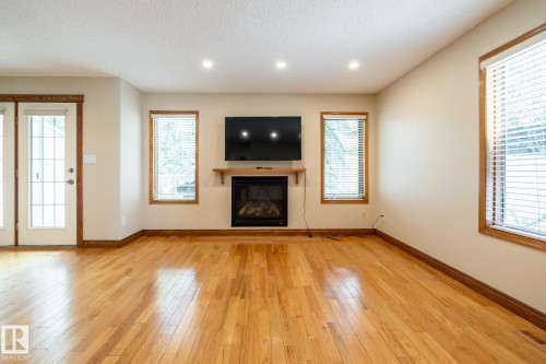 Bright room featuring wood-finish flooring, a built-in fireplace with a wood mantle, recessed lighting, and multiple windows with blinds - 4632 151 Street, Edmonton, AB - Indoor Photo Showing Living Room With Fireplace