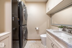 Laundry area with a stacked washer and dryer, complemented by a pebble-finish floor - 