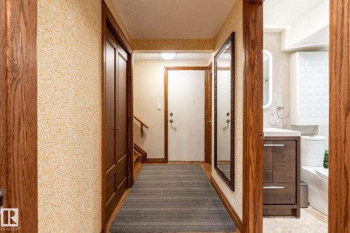 Hallway featuring wood-finish flooring, a full-length mirror, and wood trim accents - 4632 151 Street, Edmonton, AB - Indoor Photo Showing Other Room