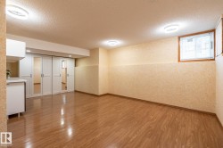 Expansive room featuring wood-finish flooring, recessed lighting, a built-in cabinetry unit with a countertop, and sliding closet doors with mirrored panels - 