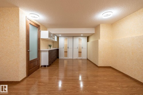 Spacious room featuring wood-finish flooring, recessed lighting, and a built-in storage unit with mirrored doors - 4632 151 Street, Edmonton, AB - Indoor