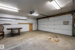 Spacious garage featuring a concrete floor, overhead fluorescent lighting, and a white paneled garage door - 