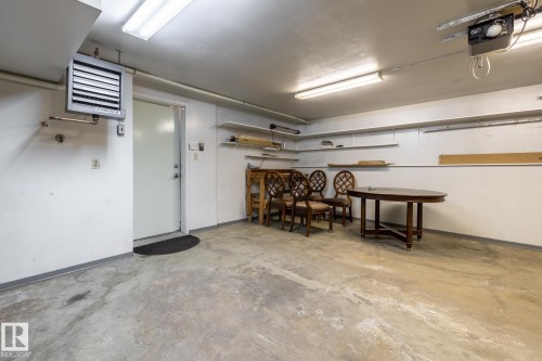Spacious garage with concrete flooring, fluorescent lighting, built-in shelving, and a wall-mounted heater unit - 4632 151 Street, Edmonton, AB - Indoor Photo Showing Garage