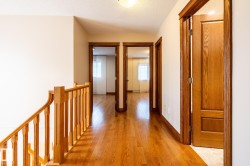 Upper-level hallway featuring wood-finish flooring and light-toned walls - 