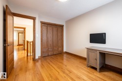 Room featuring hardwood flooring and a built-in closet with wood-panel doors - 